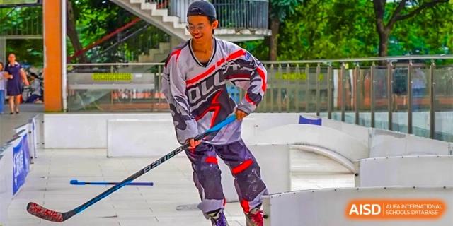A student in sports gear with a stick, playing roller hockey or floorball on an outdoor court at GDUFS International School Guangzhou.
