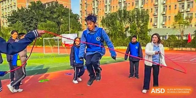 Two young boys skipping rope together on a red outdoor sports surface at GDUFS International School Guangzhou.