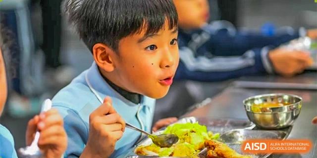GDUFS International School Guangzhou student with a surprised or happy expression eating a meal with a spoon.