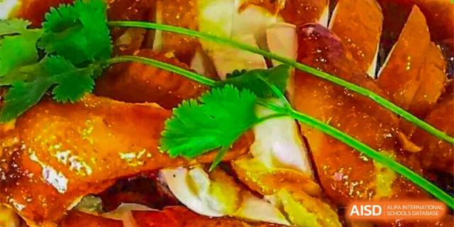 Close-up shot of a savory food item, possibly a roasted dish, garnished with fresh cilantro at GDUFS International School Guangzhou.