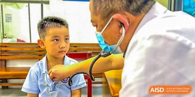 GDUFS International School Guangzhou student receiving a health check-up, with a doctor wearing a mask using a stethoscope to listen to the student's chest.