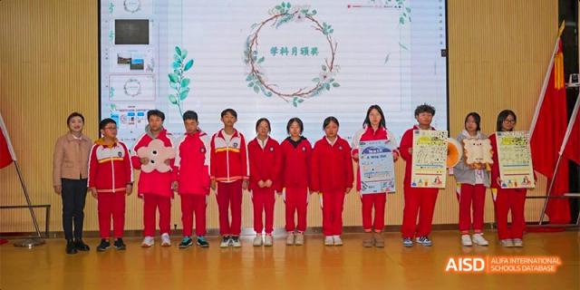A group of Guiyang Prime School students in red and white uniforms posing with awards or certificates on a stage for a presentation.