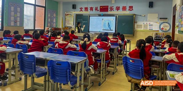 Students in a classroom at Guiyang Prime School seated at desks while a teacher lectures with a presentation displayed on a large screen.