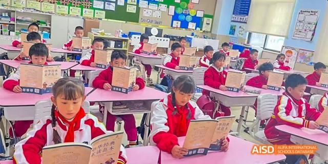 Guiyang Prime School students in red and white uniforms reading books at their desks in a classroom setting.