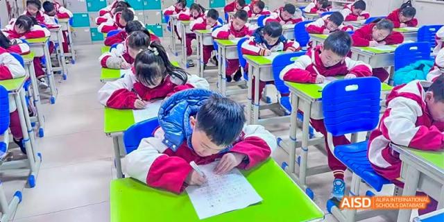 A Guiyang Prime School student, dressed in red and blue, resting their head on their desk while studying or taking a break.