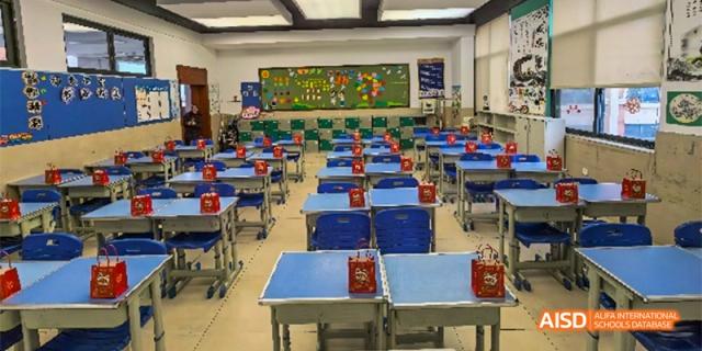 An empty classroom at Guiyang Prime School with blue and red desks, ready for a lesson.