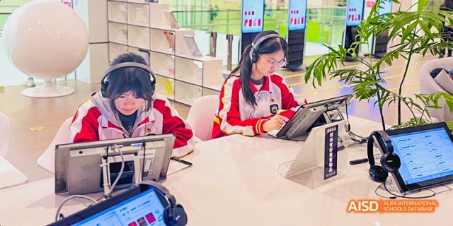 A Guiyang Prime School student wearing a headset and using a tablet or laptop at their desk for digital learning.