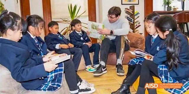 A small group of Guiyang Prime School students and a teacher/mentor discussing a topic indoors.