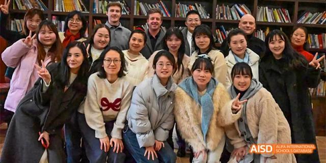 A diverse group of Guiyang Prime School students and international staff/visitors posing together for a group photo indoors.