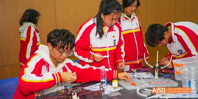Guiyang Prime School students in uniform collaborating on a hands-on science or engineering project at a table.