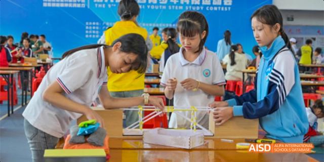 Guiyang Prime School students in yellow and blue shirts working together on a STEM project or engineering model.