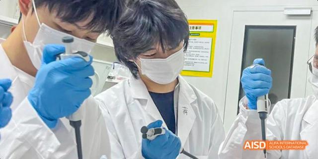 A Guiyang Prime School student wearing a mask and a lab coat, using a pipette or specialized tool for an experiment in a laboratory.
