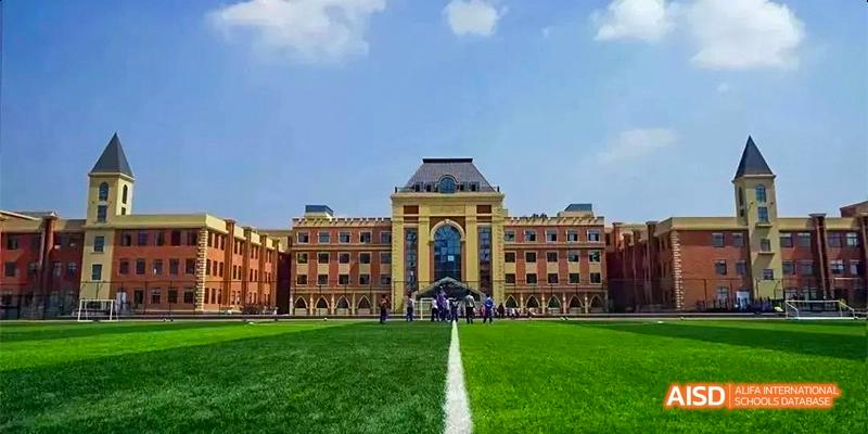 The grand main building of Guiyang Prime School, viewed across a perfectly manicured green lawn with a white dividing line.