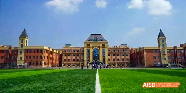 The grand main building of Guiyang Prime School, viewed across a perfectly manicured green lawn with a white dividing line.