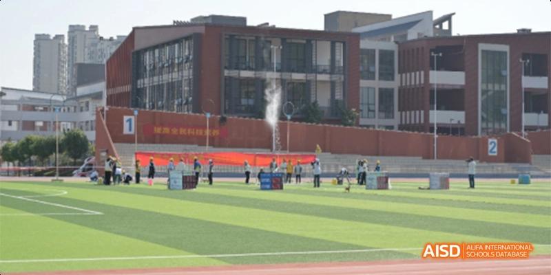 Students from Guiyang Prime School participating in an outdoor activity or training on the artificial turf field near the school buildings.