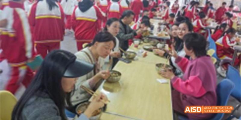 A close-up view of Guiyang Prime School students and staff eating a meal together at a long table.