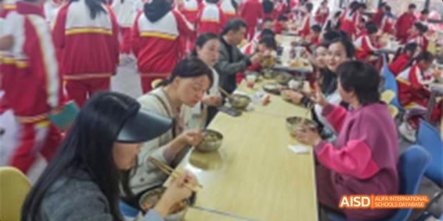A close-up view of Guiyang Prime School students and staff eating a meal together at a long table.
