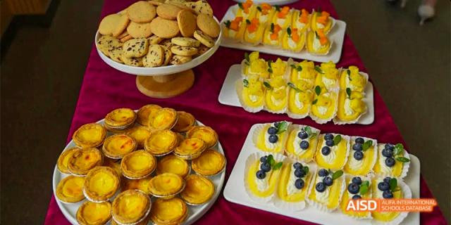 A table display of various desserts and pastries, including fruit tarts and small cakes, served at a Guiyang Prime School event.