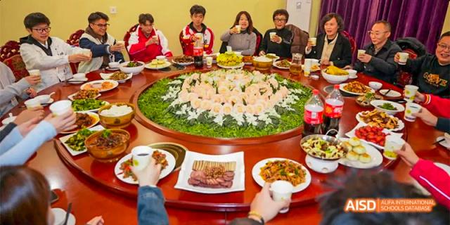 Guiyang Prime School students and staff enjoying a meal together at a large round table, featuring various dishes.