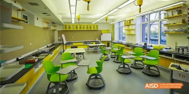 A bright, modern classroom featuring green ergonomic chairs and white desks arranged for collaboration at Beijing Haidian Kaiwen Academy.