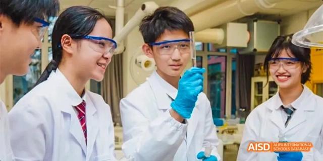 A male student in a lab coat holds up a test tube for inspection during a science practical lesson at Beijing Haidian Kaiwen Academy.