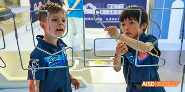 Two young students focus intently on a hands-on science experiment involving wire frames and liquid film in a classroom at Beijing Haidian Kaiwen Academy.