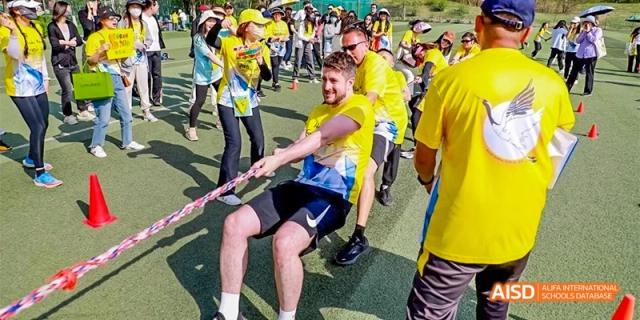 Participants show teamwork and determination while pulling the rope during an outdoor field day sports competition at Beijing Haidian Kaiwen Academy.
