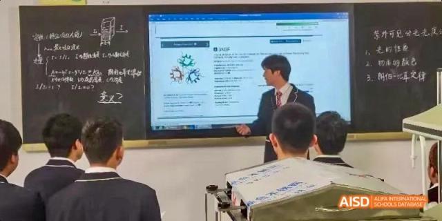 A teacher from Hangzhou World Foreign Language School is standing in front of a smart board, teaching students.