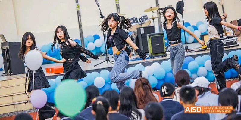 A female student at Hangzhou World Foreign Language School is performing a high-energy jump on a stage during an event.