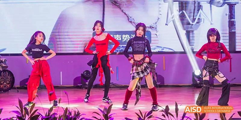 Two female students at Hangzhou World Foreign Language School are performing a dance routine on a stage.