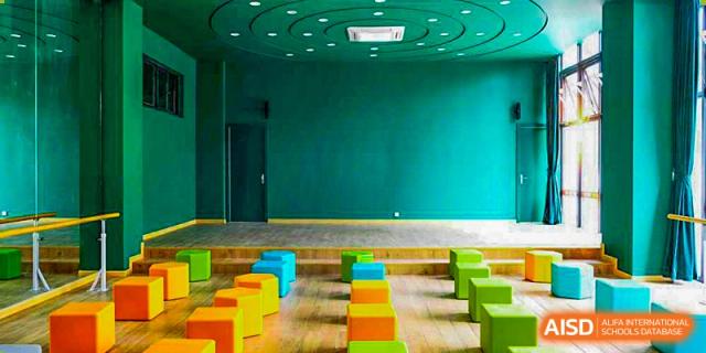 A colorful, empty seating area with bright stools and a green wall at Hangzhou World Foreign Language School.