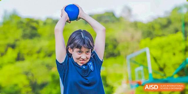A female student from Hangzhou World Foreign Language School is holding a discus and preparing to throw it.