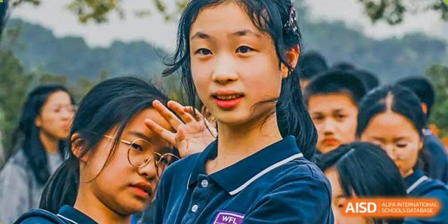 A female student at Hangzhou World Foreign Language School is smiling and waving at the camera.