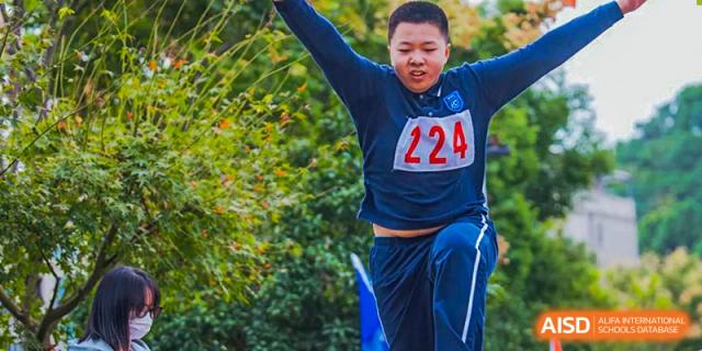 A male student at Hangzhou World Foreign Language School is running and jumping during a race, wearing a number 224 shirt.