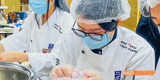 A student at Hangzhou World Foreign Language School is checking the temperature of another student with a forehead thermometer.