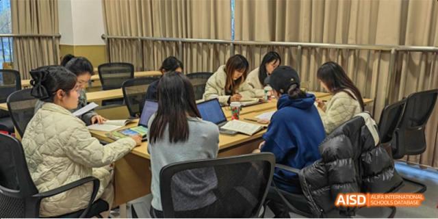 A group of students sit around a table with laptops and notebooks, deeply focused on a collaborative project. Hefei No.8 High School.
