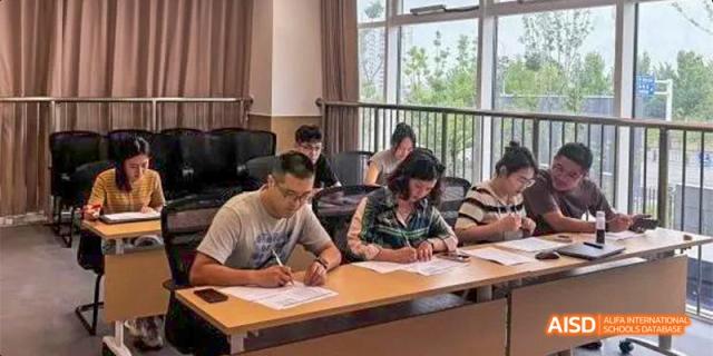 Students are seated at desks near a window, diligently filling out paperwork or taking a written exam. Hefei No.8 High School.