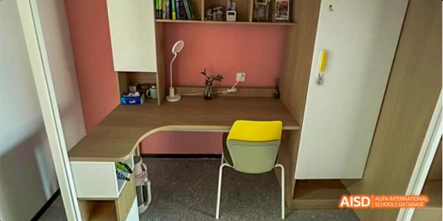 A clean, private study carrel features a built-in desk, lamp, and a yellow chair for individual learning. Hefei No.8 High School.