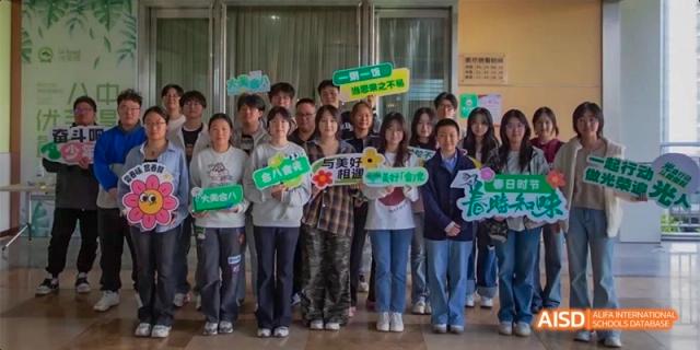 A group of students smile and hold up colorful, decorative signs during a festive school event or celebration. Hefei No.8 High School.