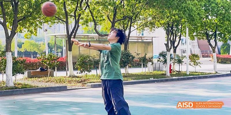 A student practices a martial arts or dance pose outdoors on a sunny day at Hefei No.8 High School.