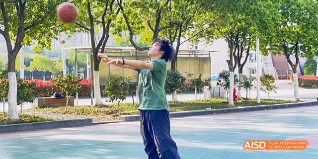 A student practices a martial arts or dance pose outdoors on a sunny day at Hefei No.8 High School.