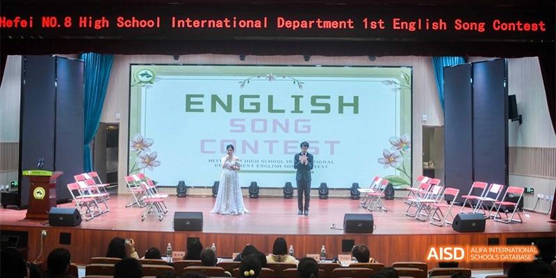 A student on a stage performing at an "English Song Contest" at Hefei No.8 High School.