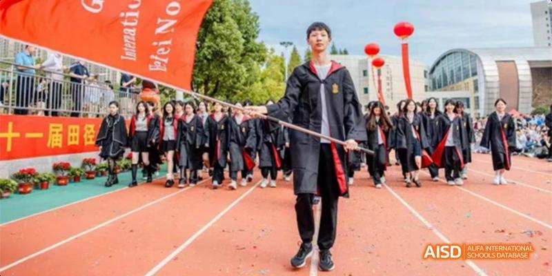 A student in a graduation robe carries a flag during a processional on the running track at Hefei No.8 High School.