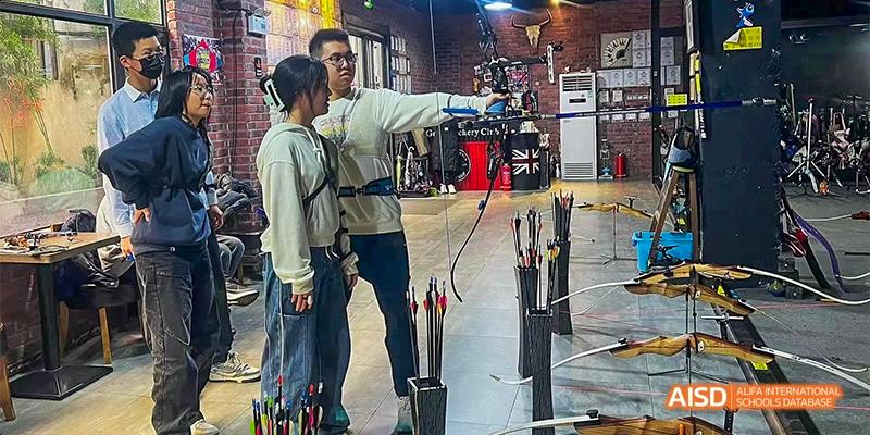 Students participate in an indoor archery session, aiming their bows at targets at Hefei No.8 High School.