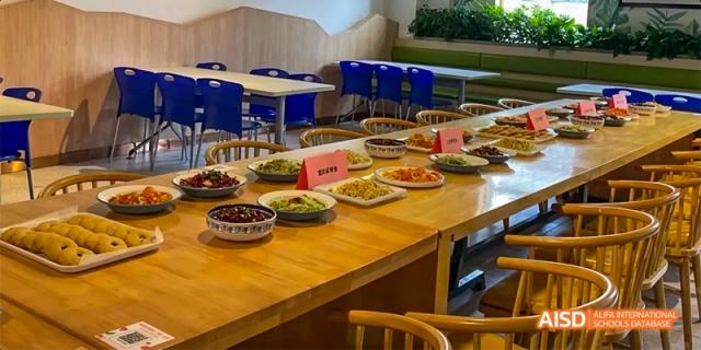 A long dining table in a cafeteria set with numerous organized plates of food at Hefei No.8 High School.