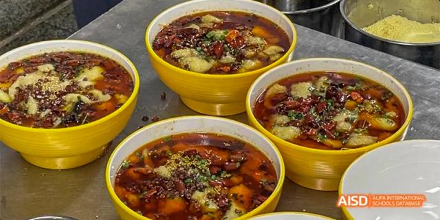 Several yellow bowls filled with a spicy red broth and various ingredients at Hefei No.8 High School.