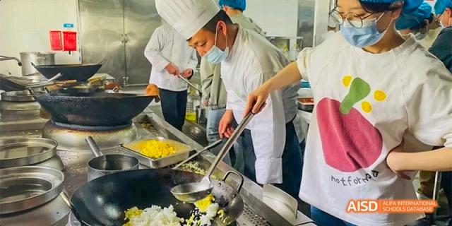 A student chef carefully tossing ingredients in a large wok over a stove at Hefei No.8 High School.