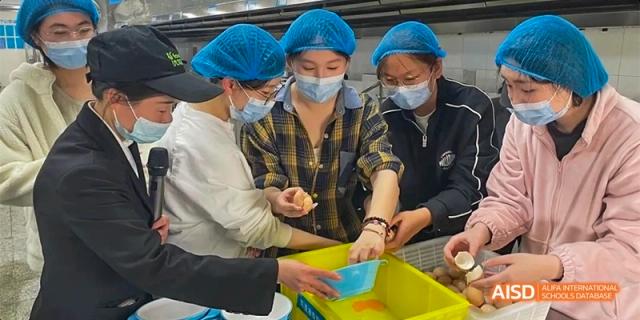 A group of students working together to prepare and sort ingredients in a tray at Hefei No.8 High School.