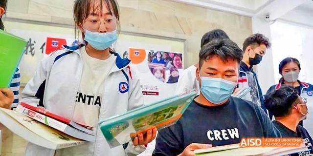 A student from Kunming No.1 High School International Education holds a book and smiles while others look on in the background.