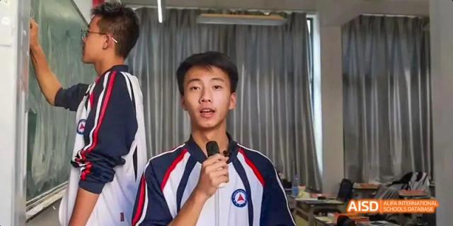A portrait of a male student from Kunming No.1 High School International Education holding a microphone and speaking.